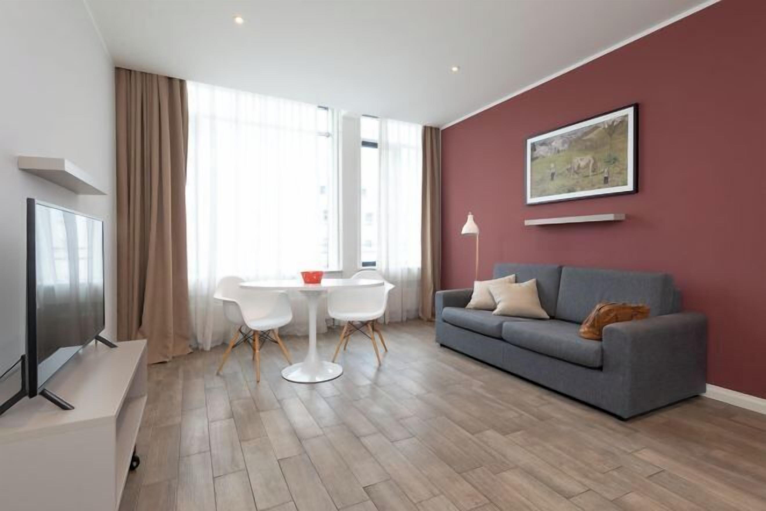 Una sala moderna con un sofá gris, una mesa blanca y un televisor.