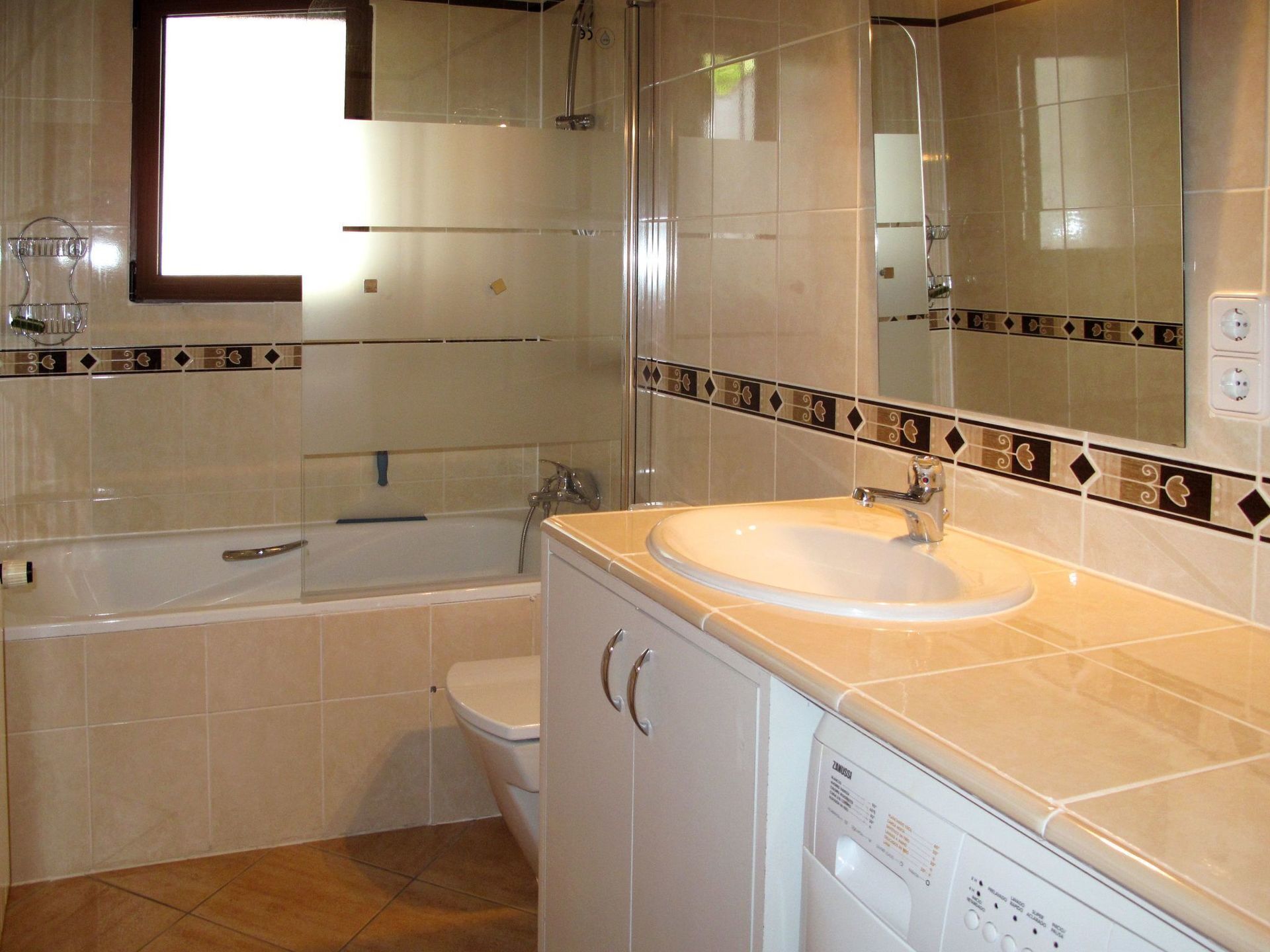 A bathroom with a bathtub, toilet, sink, and a mirror.