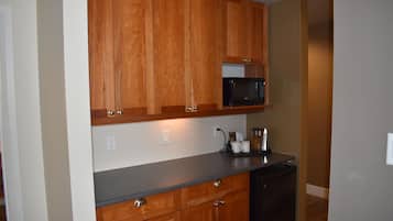 Una cocina con armarios de madera, un microondas negro y una cafetera sobre la encimera.