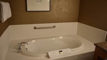 Un baño con una bañera blanca, una toalla y un cuadro enmarcado en la pared.