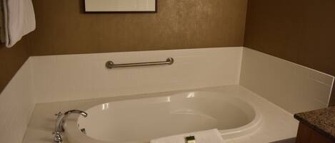 A bathroom with a white bathtub, a towel, and a framed picture on the wall.