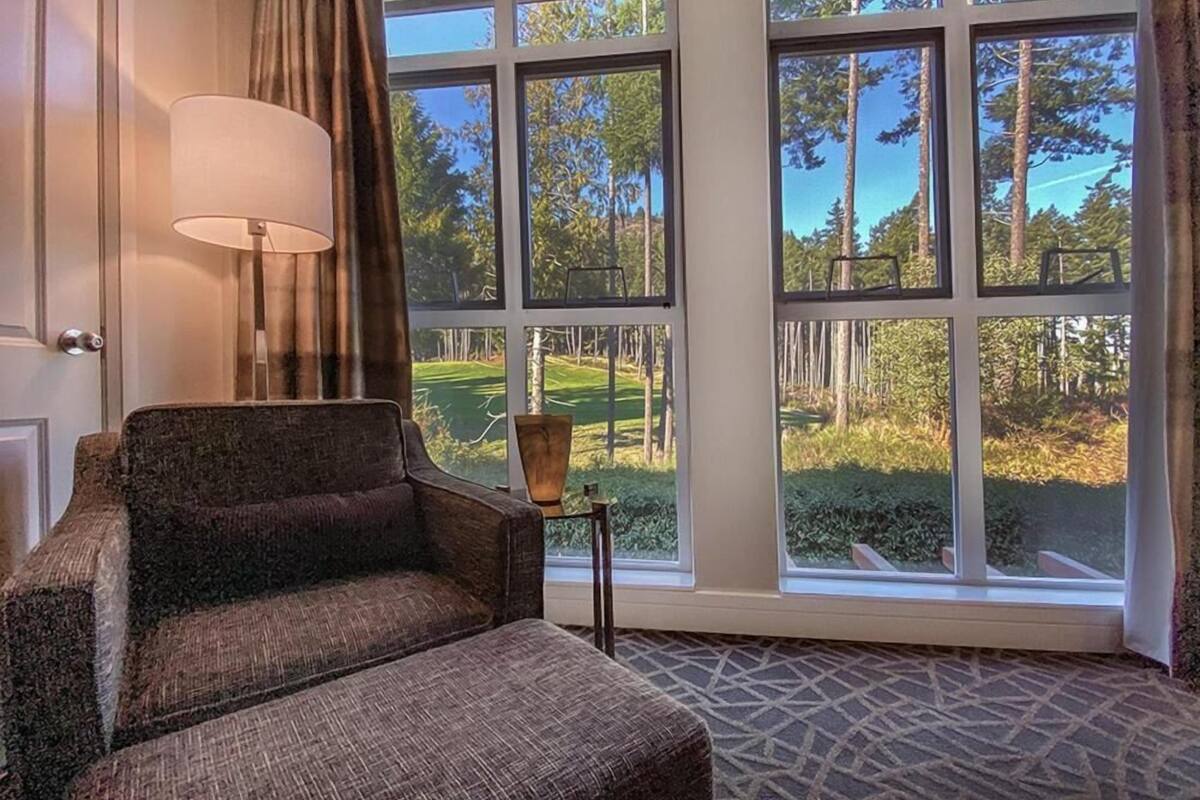 A room with a large window, a chair, a lamp, and a small table.