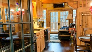 A cozy cabin-style kitchen with wooden cabinets, a dining area with a table and chairs, and a large window with a view of the outdoors.