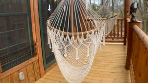 A wooden deck with two macrame hammocks hanging from the ceiling.