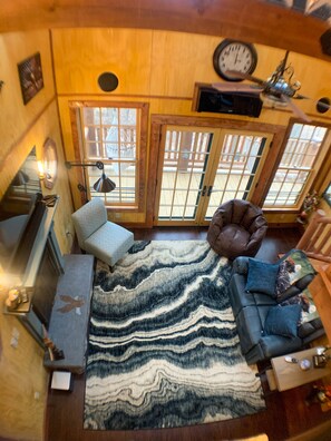 Un salon chaleureux avec un tapis à motifs, un fauteuil en cuir, un canapé et une cheminée.