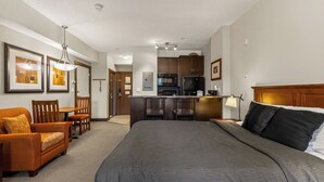 A hotel room with a large bed, a sofa, a dining table, and a kitchenette. - Time for a Getaway? Pool and A/C (Fernie)