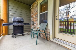 Une terrasse avec un barbecue, une chaise et un mur en pierre.