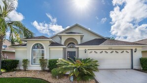 A single-story house with a garage, a well-maintained lawn, and a palm tree. - Oak Island Retreat (Kissimmee)