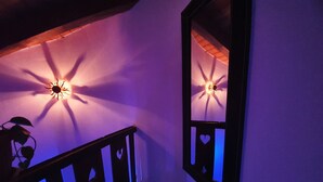 A staircase with a railing and a wall-mounted mirror reflecting a ceiling light fixture. - Villa la Tour Deluxe (Nus)