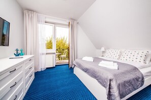 Ein Schlafzimmer mit Bett, Schminktisch, Fenster und Balkon.