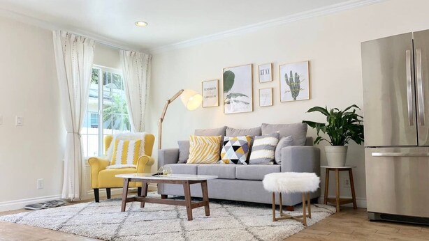 Una sala de estar con sofá, sillón, mesa de centro y una planta en maceta.