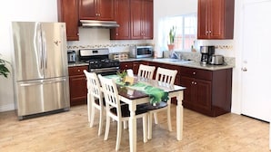 Una cocina moderna con armarios de madera, electrodomésticos de acero inoxidable y una mesa de comedor con sillas.