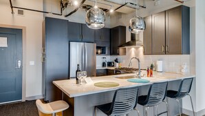 Una cocina moderna con una isla central, taburetes de bar e iluminación colgante.