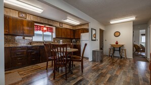 A spacious kitchen with wooden cabinets, a dining area with a table and chairs, and a refrigerator. - Shoshone Canyon House- Great Location, Canyon Views (Cody)