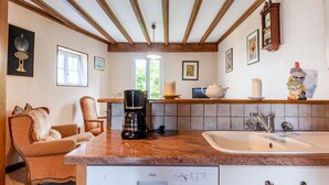 A kitchen with a coffee maker, a sink, and a chair. - Cosy apartment in villa for 4 guests with WIFI, TV, terrace, pets allowed and panoramic view (Barneville-carteret)