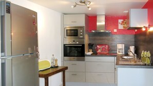A modern kitchen with stainless steel appliances, a wooden table, and a red backsplash.