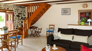 A cozy living room with a staircase, wooden furniture, a black sofa, and a dining area.