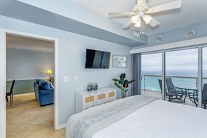 Ein Schlafzimmer mit einem großen Bett, einem Fernseher, einem Schminktisch und einem Balkon mit Meerblick.