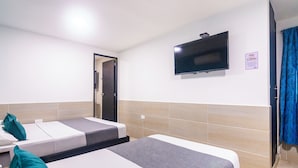 Une chambre d’hôtel avec deux lits simples, un téléviseur à écran plat fixé au mur et une porte donnant accès à la salle de bain.