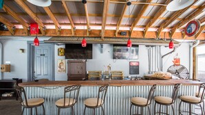 A bar area with a wooden ceiling, metal bar stools, and a counter. - BEAUTIFULLY  CONDO IN LEGENDS GOLF RESORT (Myrtle Beach)