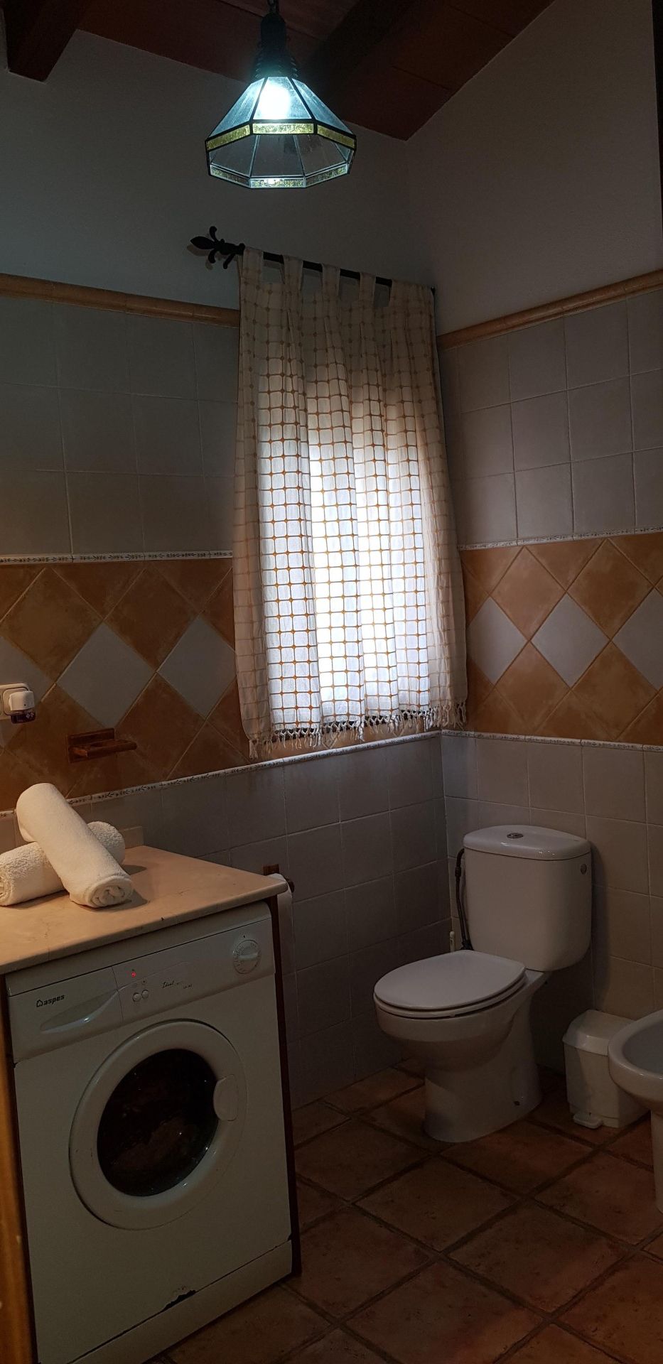 A compact bathroom with a washing machine, a toilet, and a sink.