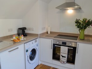 A compact kitchen with a washing machine, oven, and coffee maker.
