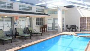 Una piscina interna con sedie a sdraio e zona pranzo.