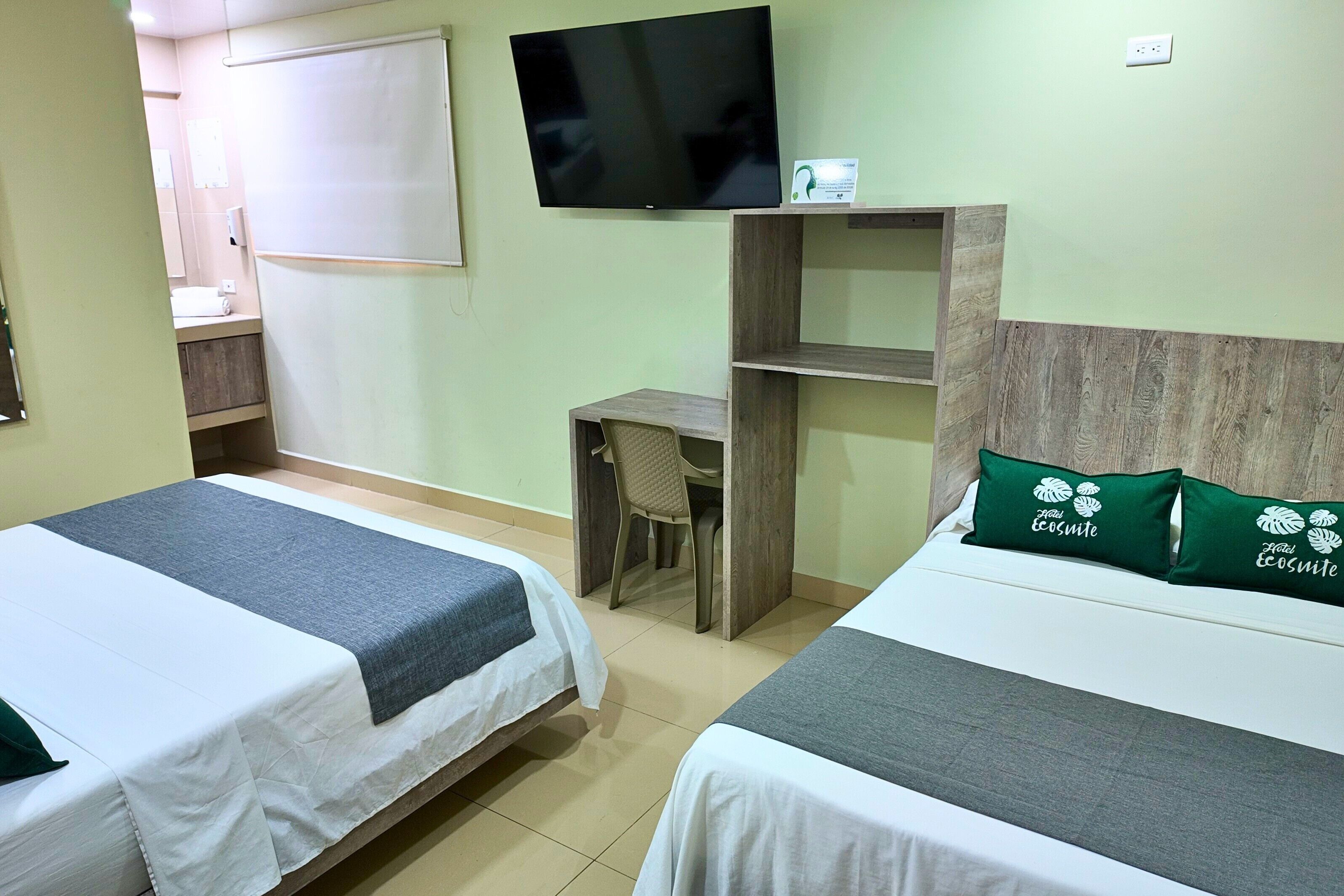 Quarto de hotel com duas camas, televisão, escrivaninha e uma cadeira.