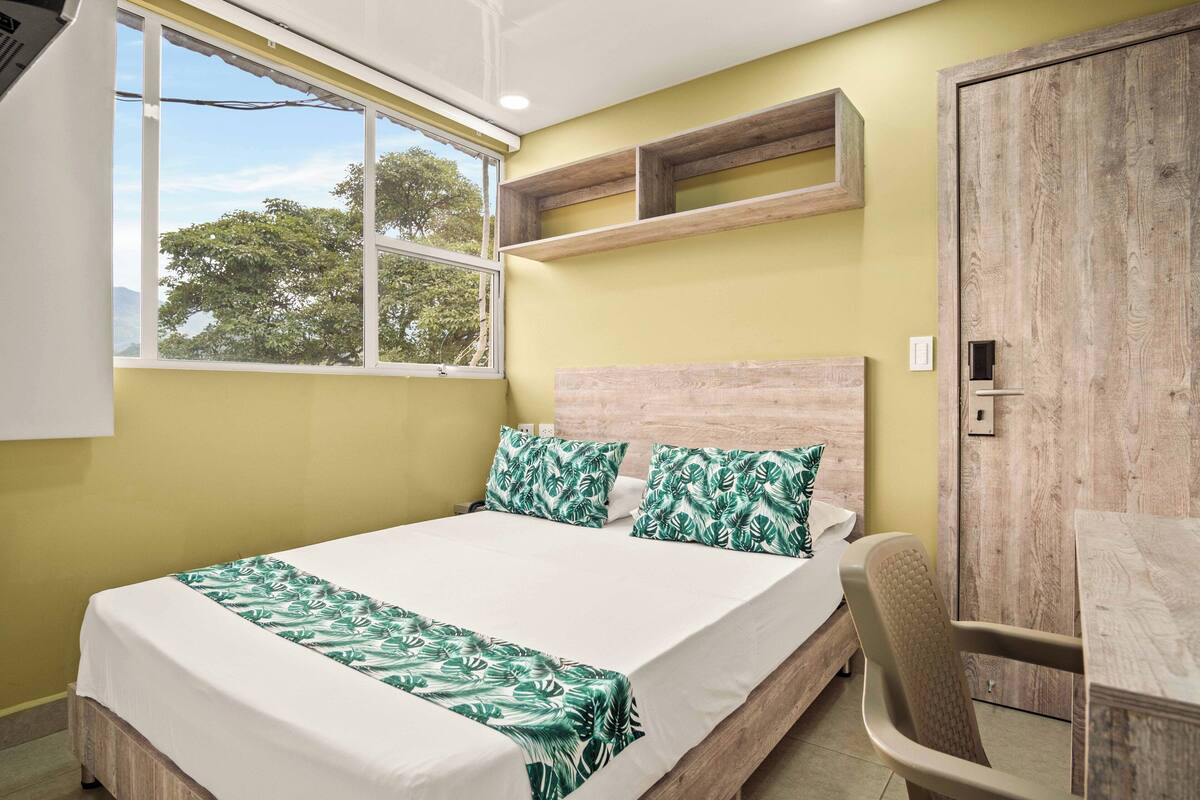 Una habitación con una cama, cabecero de madera, una ventana y un armario de madera.
