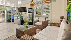 Uma área de estar moderna com móveis de vime, uma mesa de centro de vidro e uma televisão.