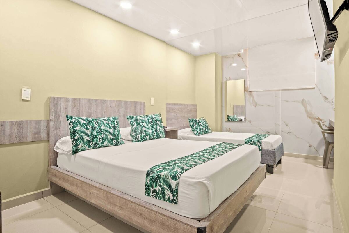 Habitación de hotel con dos camas, cabecero de madera, pared de mármol y un espejo grande.