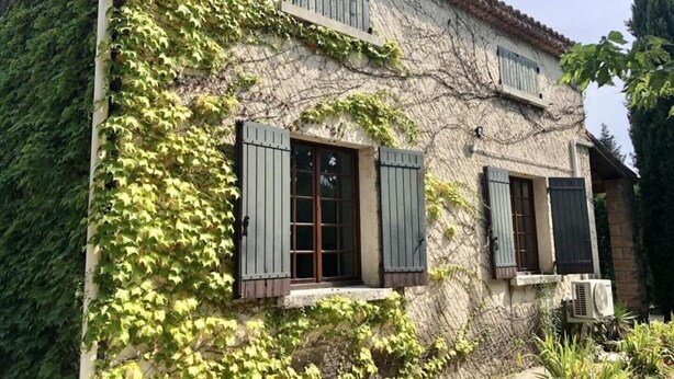 Un bâtiment rustique aux murs recouverts de lierre et aux fenêtres dotées de volets en bois.