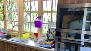 Une cuisine avec des meubles en bois, un four en acier inoxydable et une fenêtre donnant sur les arbres.