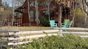A rustic cabin with a porch, outdoor seating, and a sign that reads "Peter". - Charming Petersen Cottage Rustic Luxury  (Pine Valley)