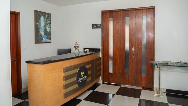 A reception desk with a logo, a wooden door, a framed picture, and a checkered floor. - Ayenda 1131 Casa Valencia (Manizales)