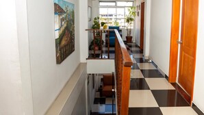 A hallway with a checkered floor, a staircase, a wooden door, and a painting on the wall. - Ayenda 1131 Casa Valencia (Manizales)