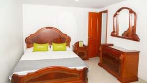 A bedroom with a wooden bed, two green pillows, a wooden dresser, and a mirror on the wall. - Ayenda 1131 Casa Valencia (Manizales)
