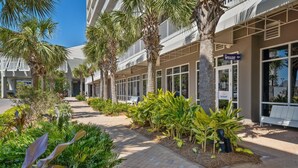 A hotel with a modern design, featuring a pathway lined with palm trees and various plants.