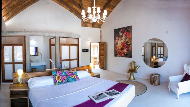 A spacious bedroom with a large bed, a chandelier, a mirror, and a view of the outside. - Hotel Pochote Mazunte (Santa María Tonameca)