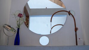 A bathroom with a large mirror, a blue vase with flowers, and a towel rack. - Hotel Pochote Mazunte (Santa María Tonameca)