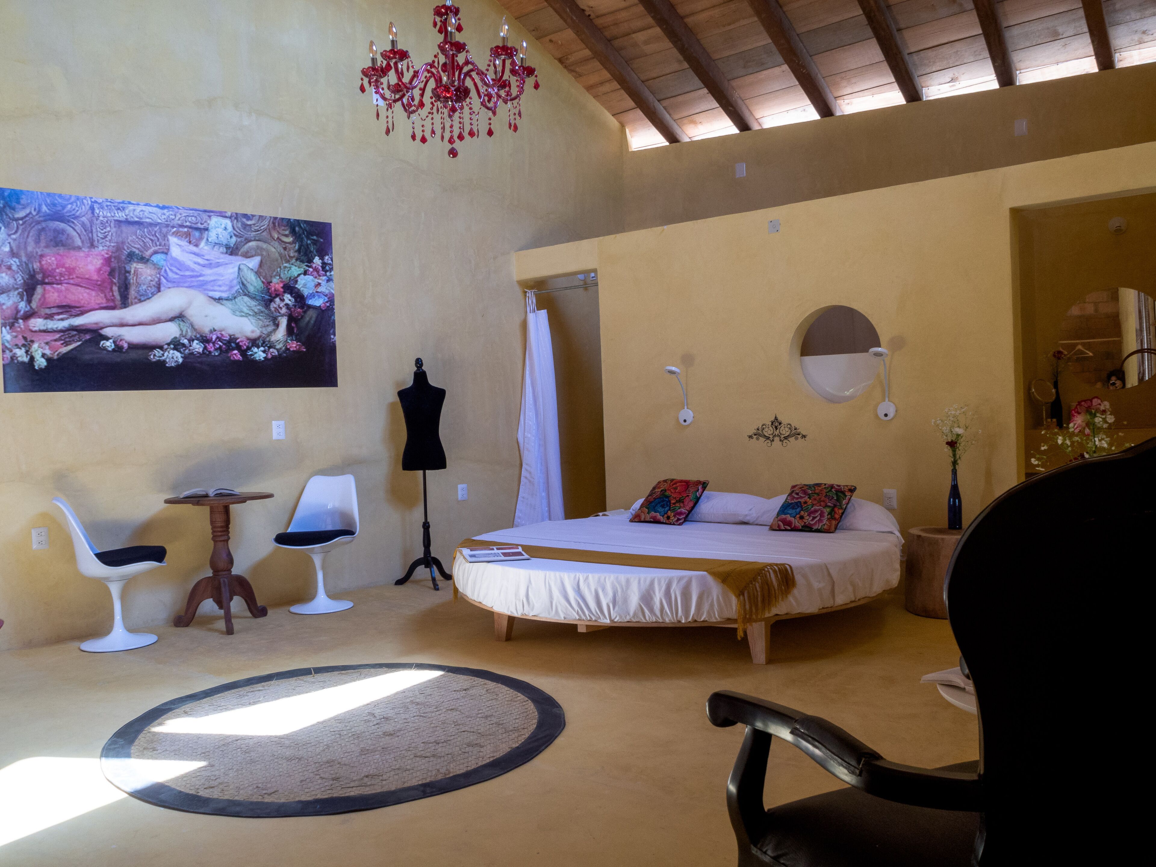 A bedroom with a bed, a chair, a vanity, and a chandelier.