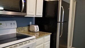 A kitchen with white cabinets, a microwave, a toaster, a stainless steel refrigerator, and a stove. - Hidden Treasure! Charming ground floor condo in waterfront complex. (Marble Falls)