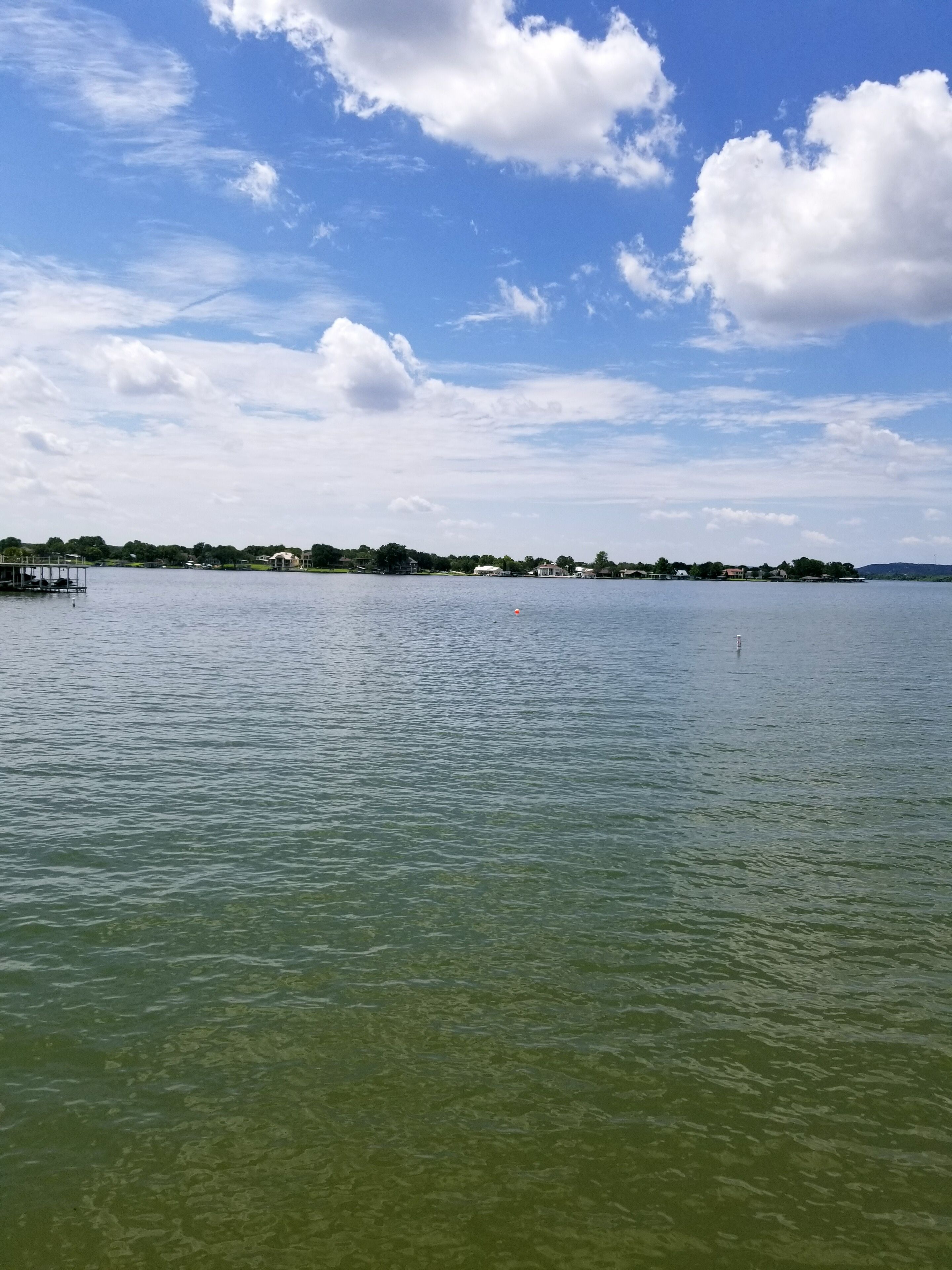 Un lago calmo con cielo sereno e edifici in lontananza.