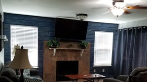 A living room with a fireplace, a ceiling fan, and a flat-screen TV mounted above it. - Hidden Treasure! Charming ground floor condo in waterfront complex. (Marble Falls)