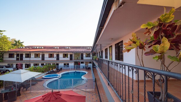 Ein Innenhof mit Schwimmbecken, Sitzgelegenheiten im Freien und einem Balkon mit Geländern.