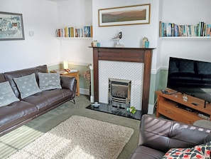 Ein Wohnzimmer mit Kamin, Bücherregalen, einer Couch und einem Fernseher.