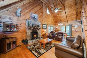 A cozy cabin interior with a stone fireplace, leather furniture, and wooden walls. - A Dream Come True 2 Bedroom Cabin by RedAwning (Sevierville)