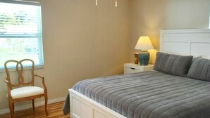 A bedroom with a bed, nightstand, lamp, chair, and window with blinds. - Beach Style House w/ large backyard, close to fishing, canoeing, and beaches (Bradenton)