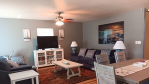 A living room with a sofa, TV, dining table, and chairs. - Beach Style House w/ large backyard, close to fishing, canoeing, and beaches (Bradenton)