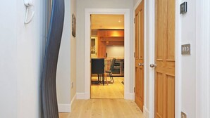 Un pasillo que conduce a una cocina con armarios de madera y una zona de comedor.